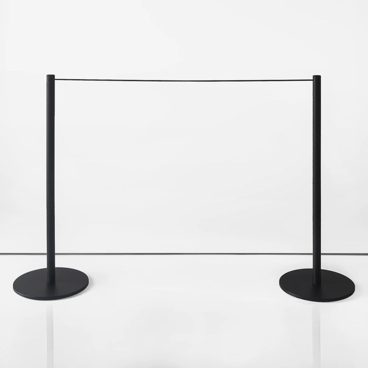 Two black slim metal stanchions in museum with a white background setting