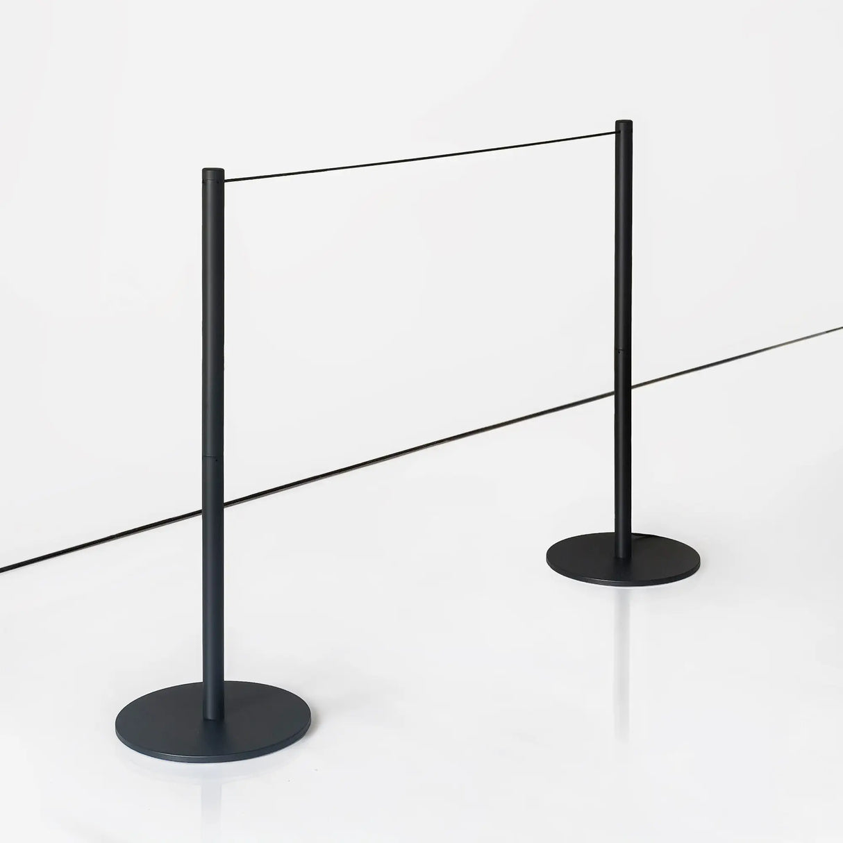 Two low profile stanchion posts with thin ropes in gallery with a white background