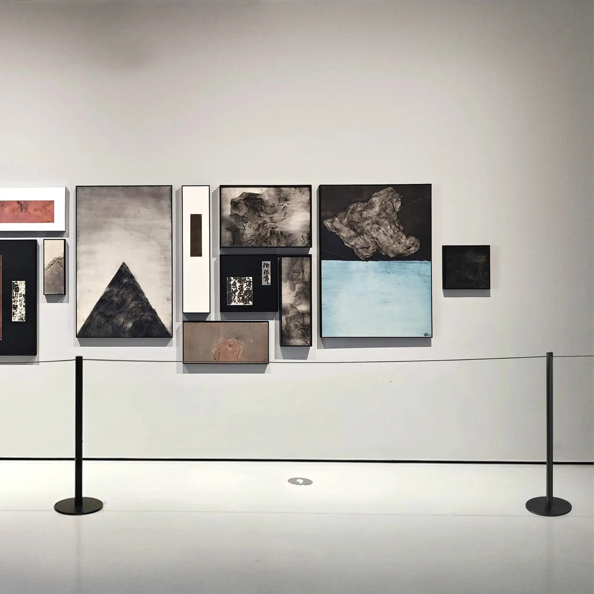 Art gallery slim stanchions with various framed artworks on a wall.