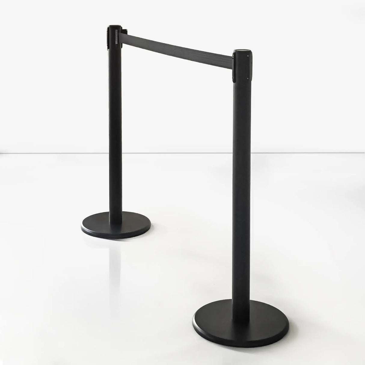 Two black stanchion barriers with retractable belts on a white background