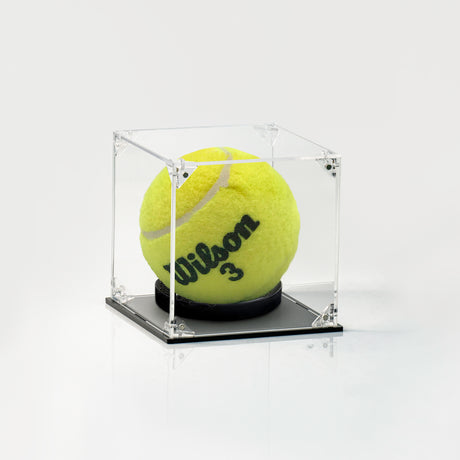 A yellow tennis ball with 'Wilson 3' printed on it, displayed inside a clear acrylic cube case with a black base on a white background.